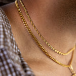 3mm gold rope chain and 4mm gold Cuban chain necklaces layered around the neck, close-up view