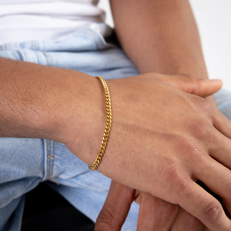 Gold curb chain bracelet worn on the wrist, close-up view