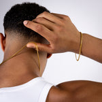 Gold curb chain bracelet worn on the wrist with matching curb chain worn around the neck.