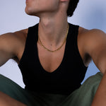 5mm gold Figaro chain necklace worn around the neck with a black tank top, front view