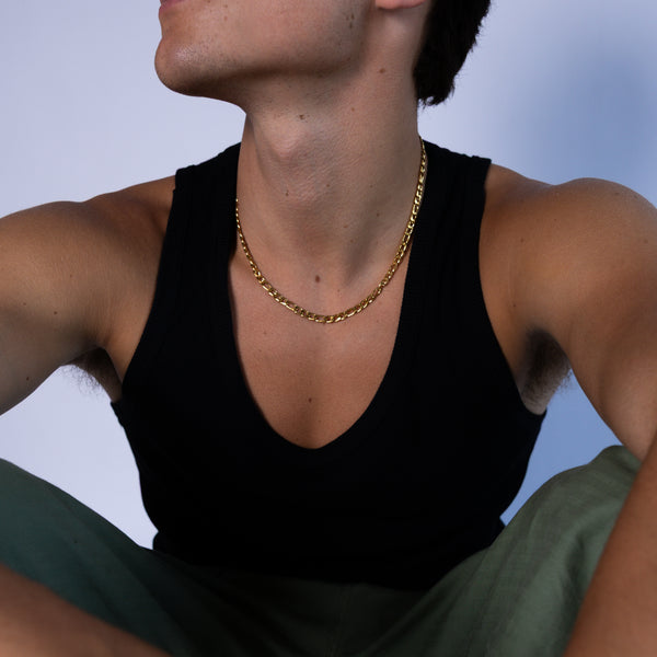 5mm gold Figaro chain necklace worn around the neck with a black tank top, front view