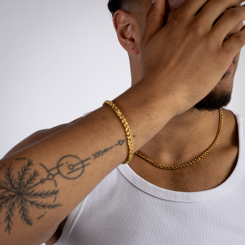 5mm gold wheat chain necklace worn around the neck whilst weaing white vest, matching 5mm wheat bracelet in view. 