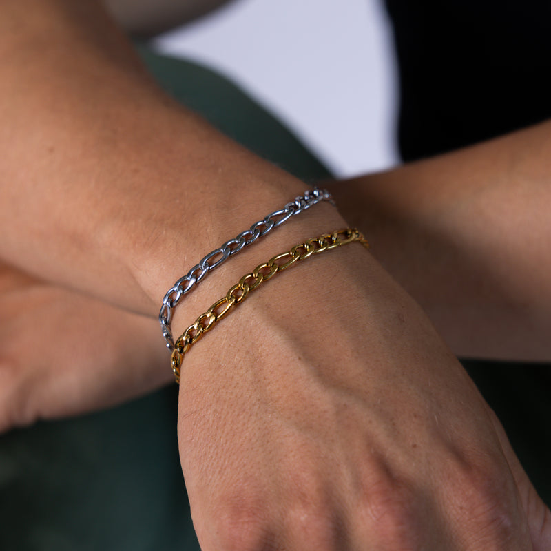 5mm gold and silver figaro chain bracelets worn on the wrist, close-up view