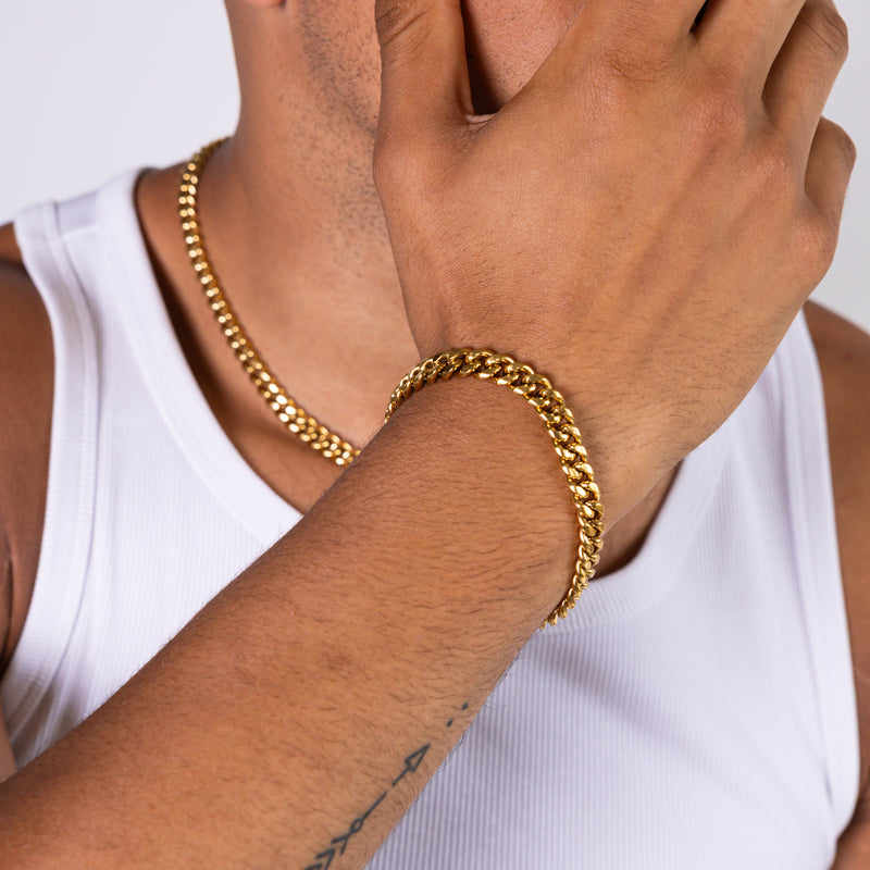 8mm gold Cuban bracelet and matching necklace worn with a white tank top, close-up view