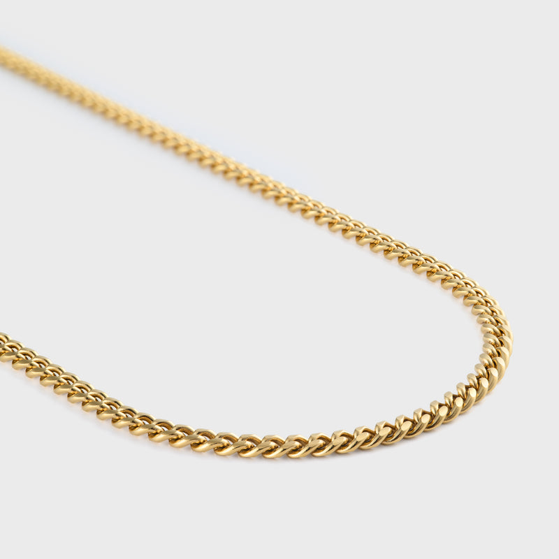 Gold chain necklace on a light grey background