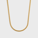 Gold chain necklace on a light grey background