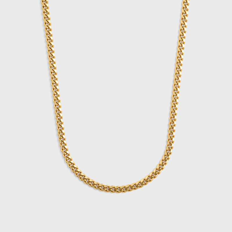 Gold chain necklace on a light grey background