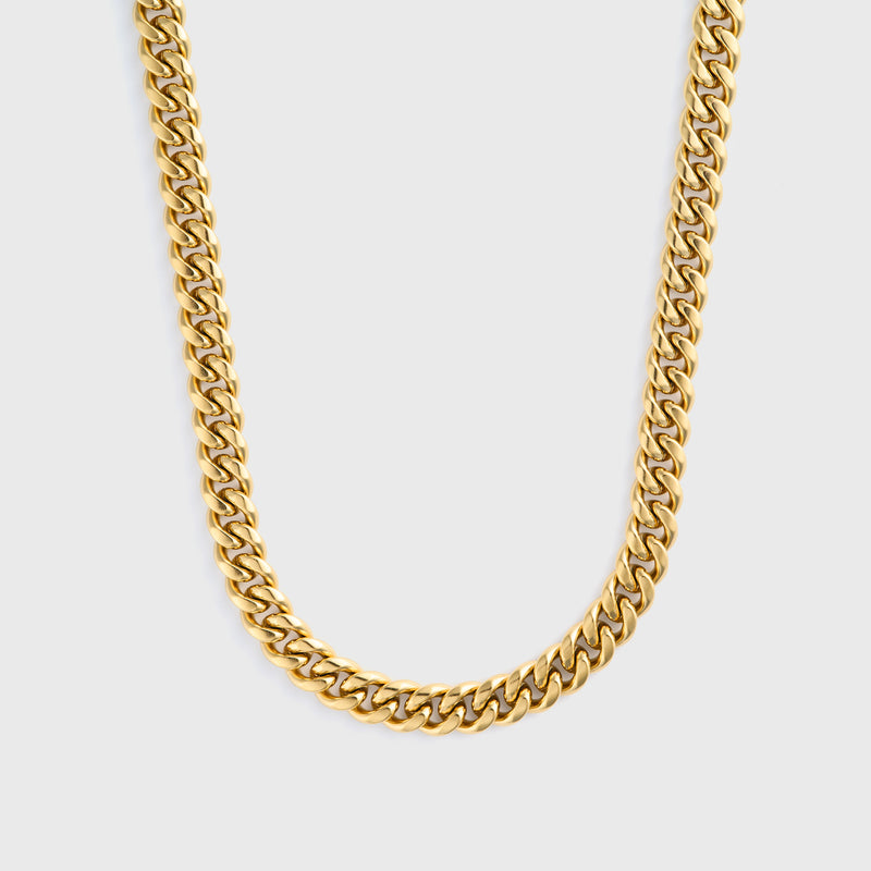 Gold cuban chain necklace on a light grey background
