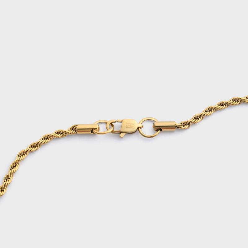 Gold rope chain clasp shot on a light grey background