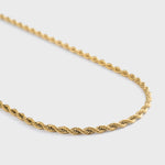 Gold rope chain necklace on a light grey background