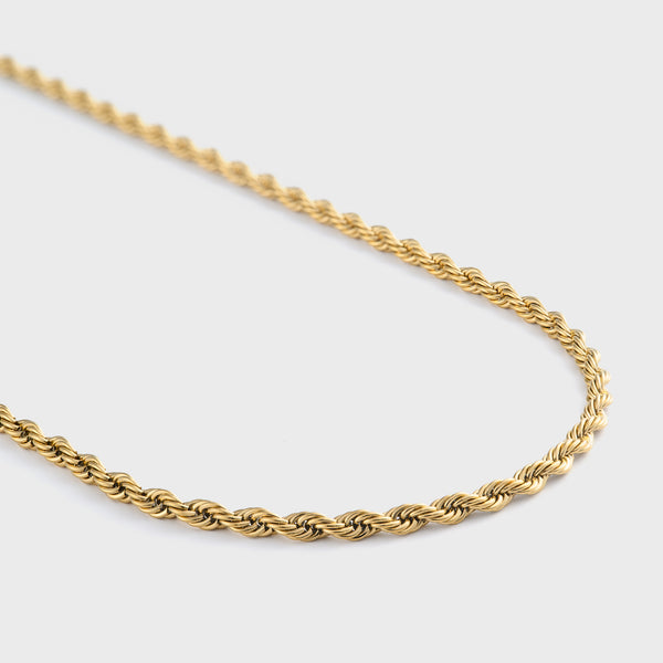 Gold rope chain necklace on a light grey background