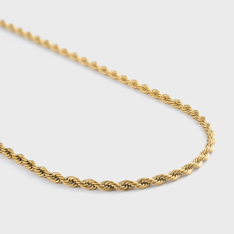 Gold rope chain necklace on a light grey background