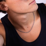 Silver rope chain necklace worn around the neck with black vest, front angled view