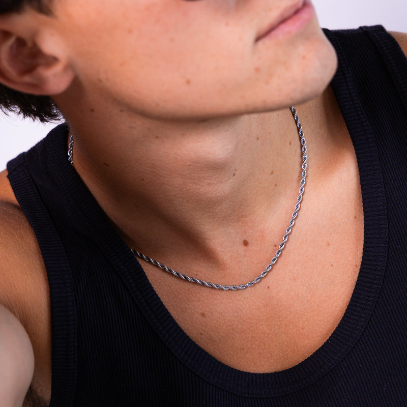 Silver rope chain necklace worn around the neck with black vest, front angled view