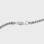 Close-up of a silver wheat chain clasp on a grey background