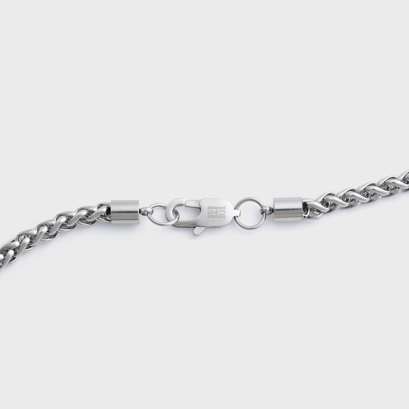 Close-up of a silver wheat chain clasp on a grey background