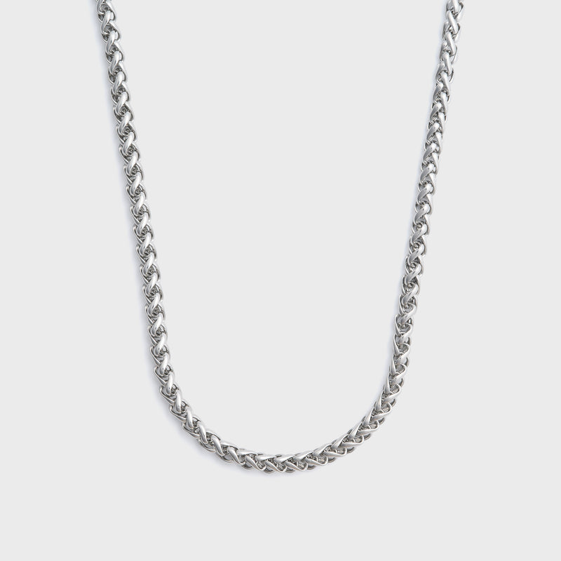 Silver wheat chain necklace on a light grey background
